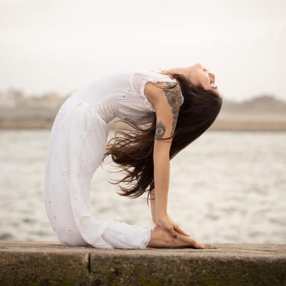 Yoga ao ar livre na praia com mulher em pose de estiramento e relaxamento, prática de bem-estar e mindfulness no Lotus Studio.