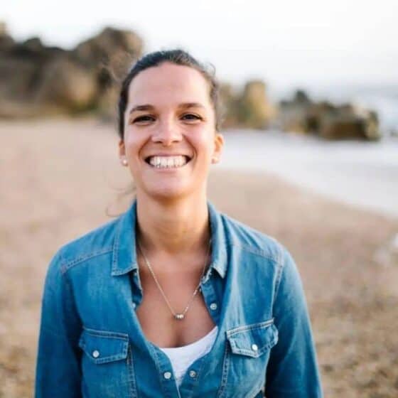 Mulher sorridente na praia, desfrutando de um momento de bem-estar e relaxamento no Lotus Studio, especializado em massagens, terapias holísticas e rejuvenescimento.